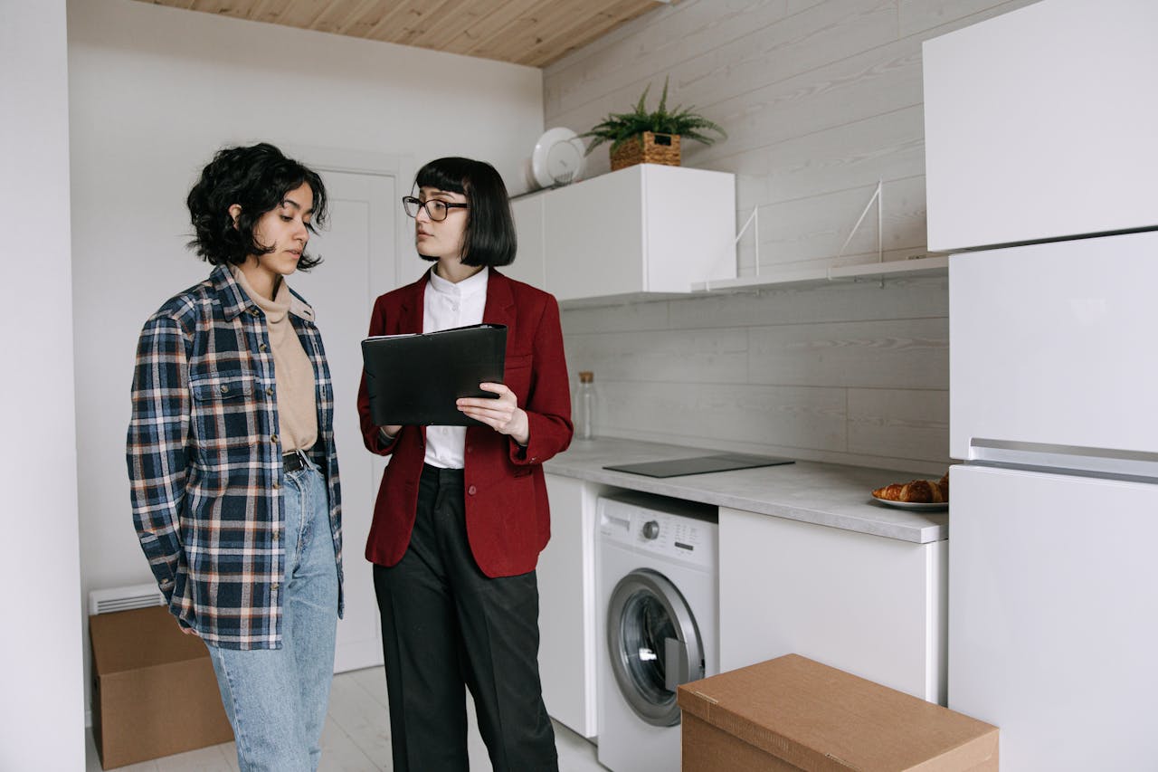 Real estate agent discussing home details with a client in a modern kitchen setting.